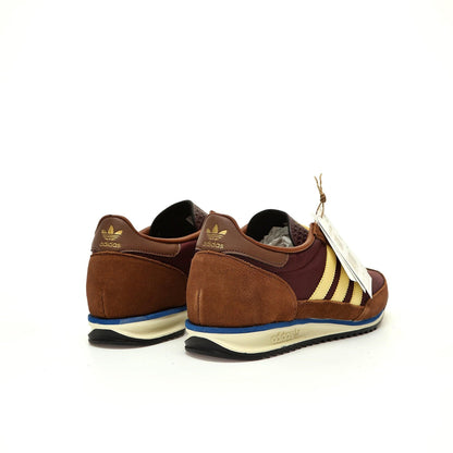 Brown Adidas sneakers with a tag on a white background