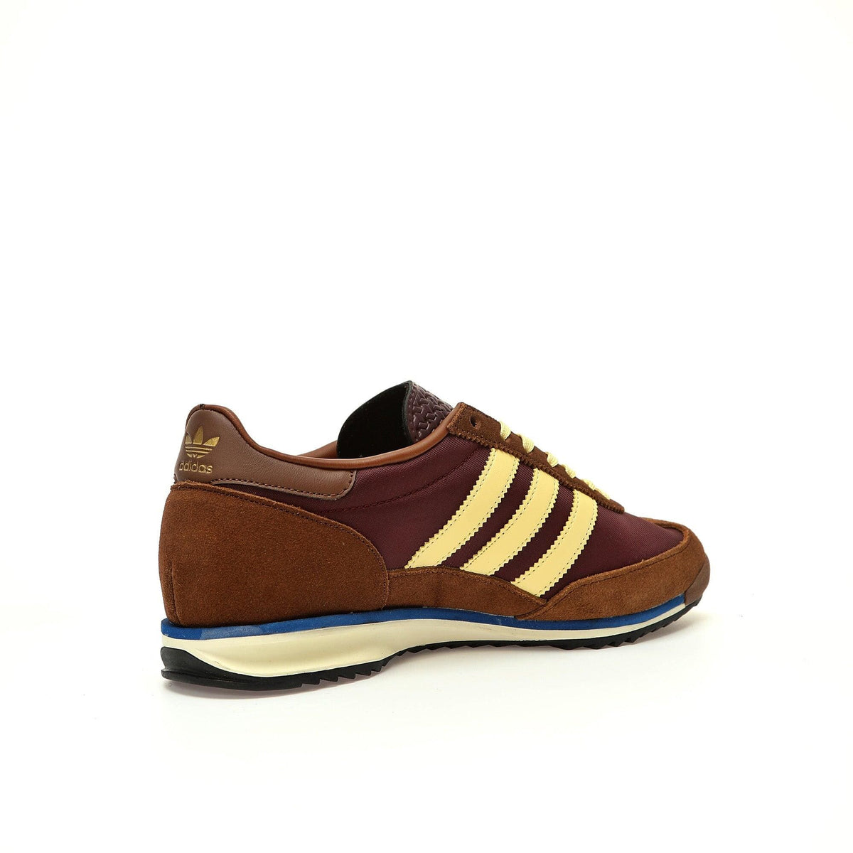 Brown Adidas sneaker with yellow stripes on a white background
