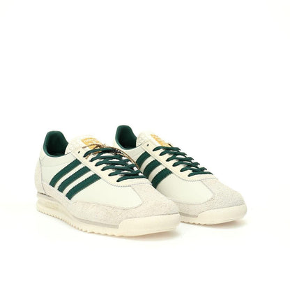 Pair of white sneakers with green stripes on a white background