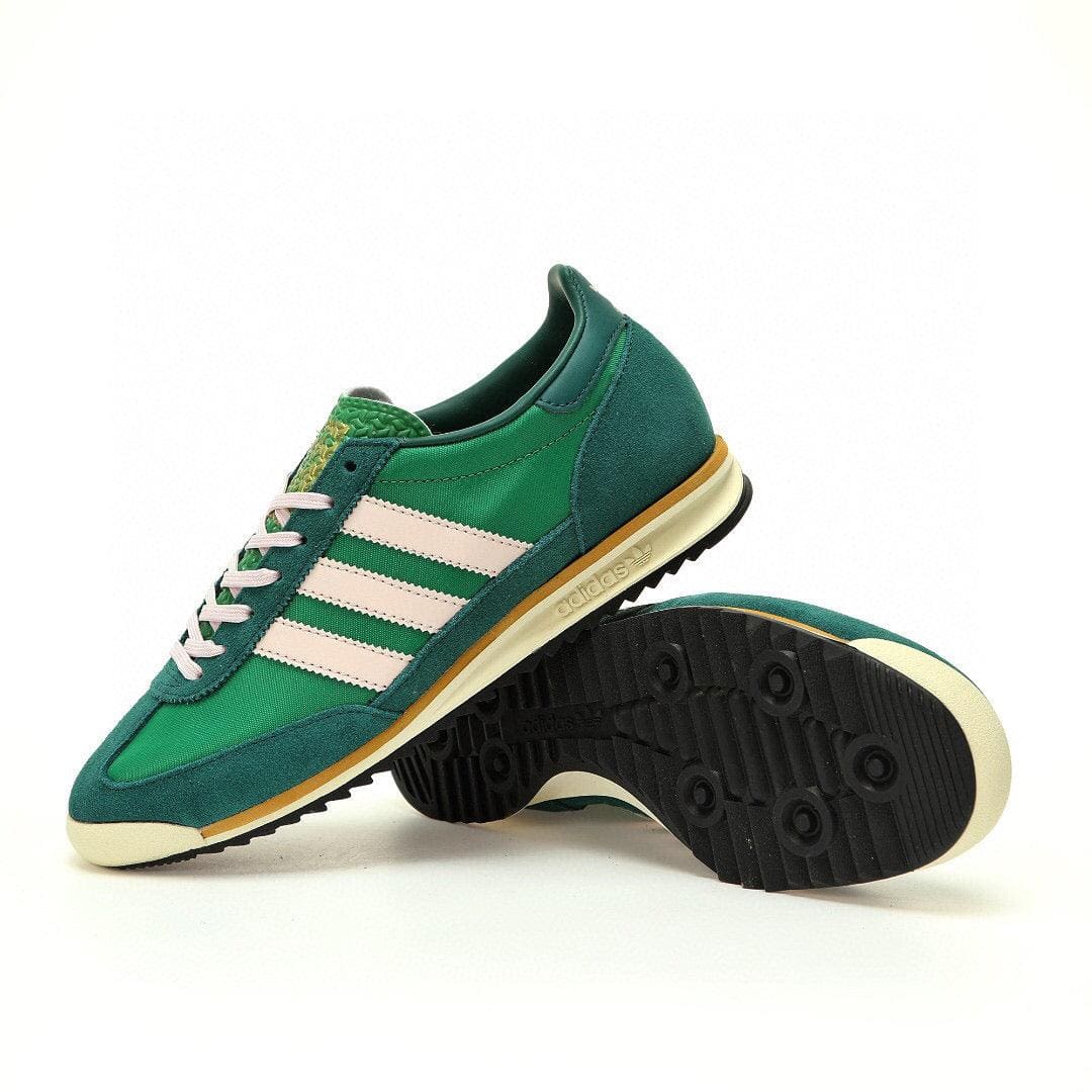 Green Adidas sneakers with white stripes on a white background