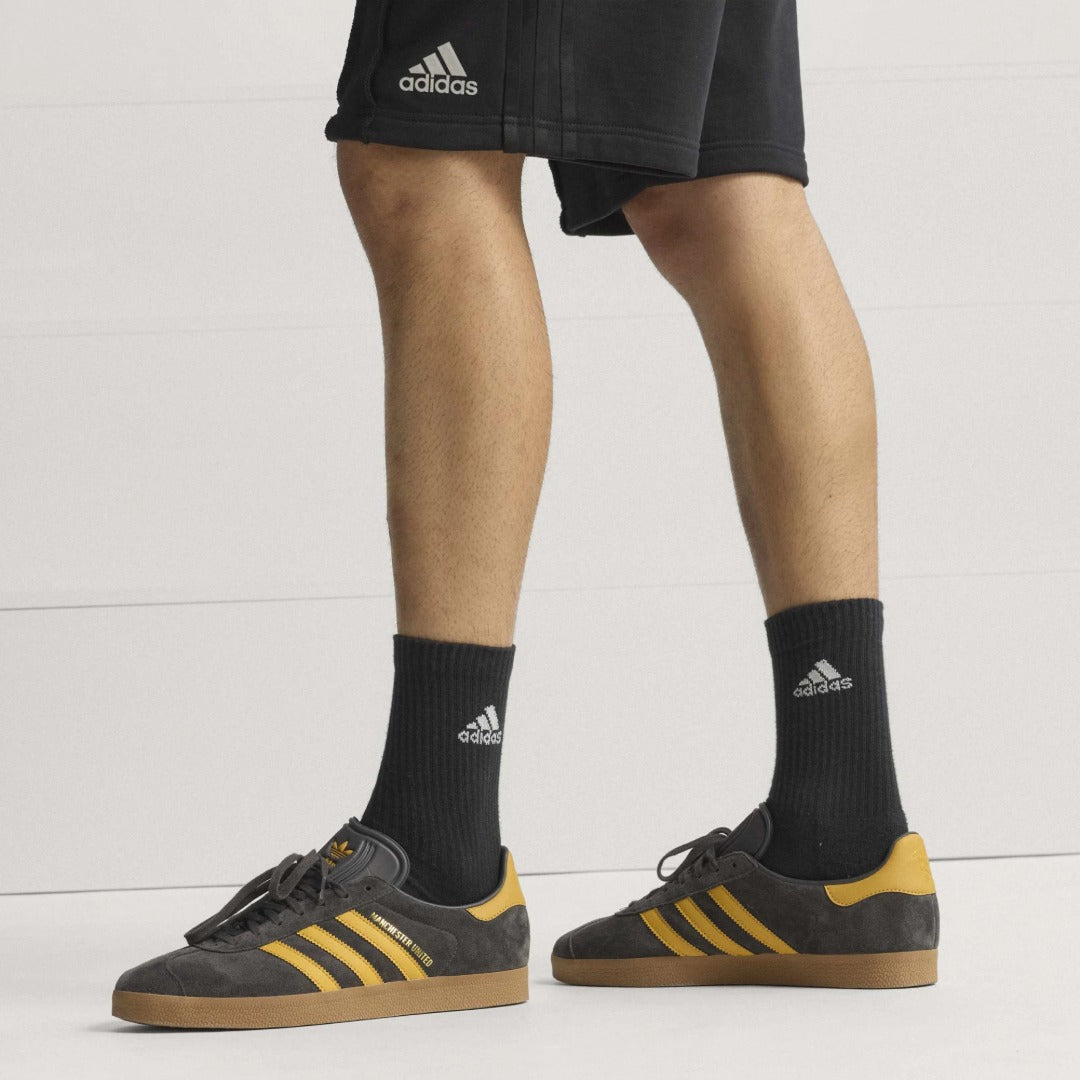 Person wearing black Adidas socks with a white background