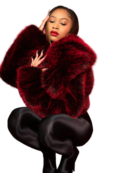 Woman wearing a red fur coat sitting on a red couch with a red background