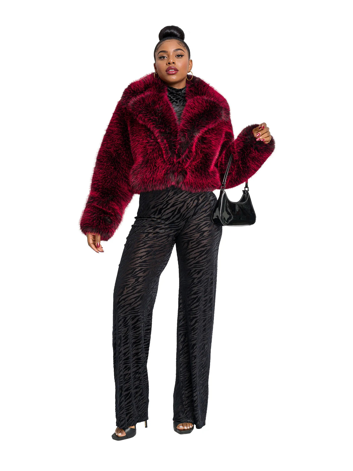 Person wearing a red faux fur jacket and black pants on a white background