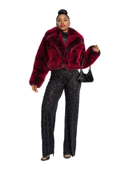 Person wearing a red faux fur jacket and black pants on a white background