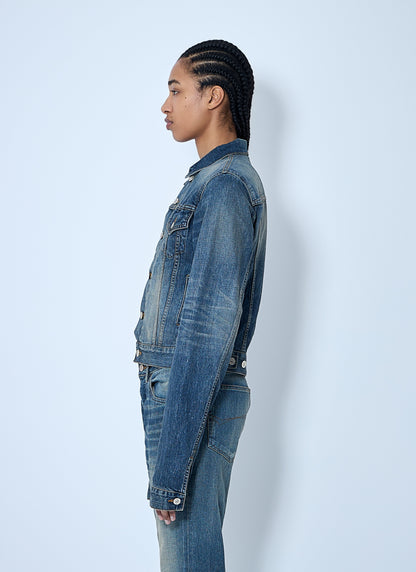 Person wearing a blue denim jacket and jeans against a white background