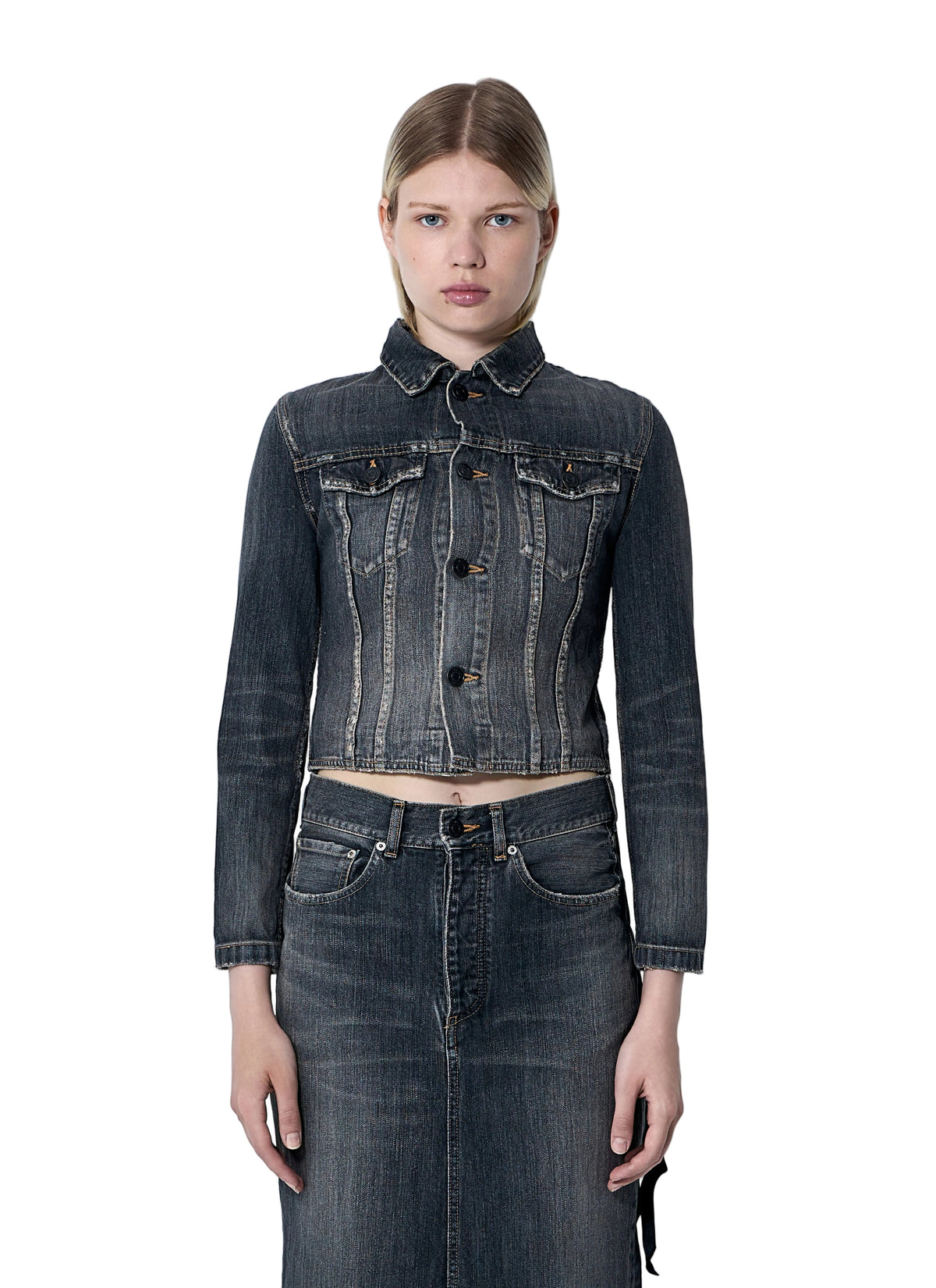 Woman wearing a dark denim jacket and skirt against a light gray background