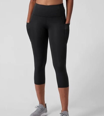 Person wearing black capri leggings on a light gray background