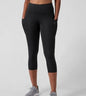 Person wearing black capri leggings on a light gray background