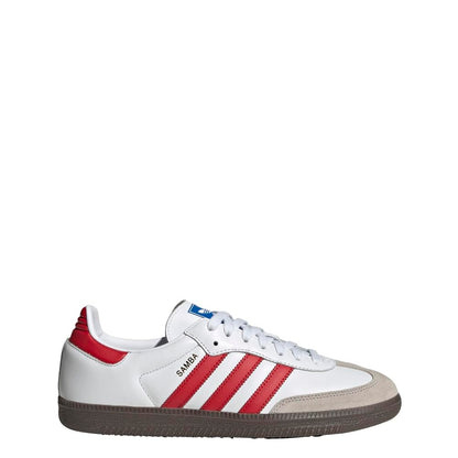 A white Adidas Samba sneaker with red three-stripes, a red heel tab, a beige suede toe cap, and a dark brown gum sole, shown from the side on a white background.