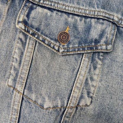 Close-up of a blue denim jacket with a button and stitching details.