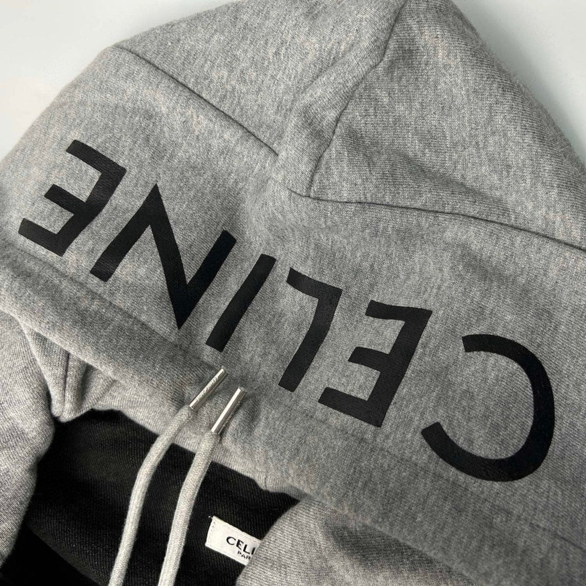 Gray hoodie with 'CELINE' branding on a light gray background