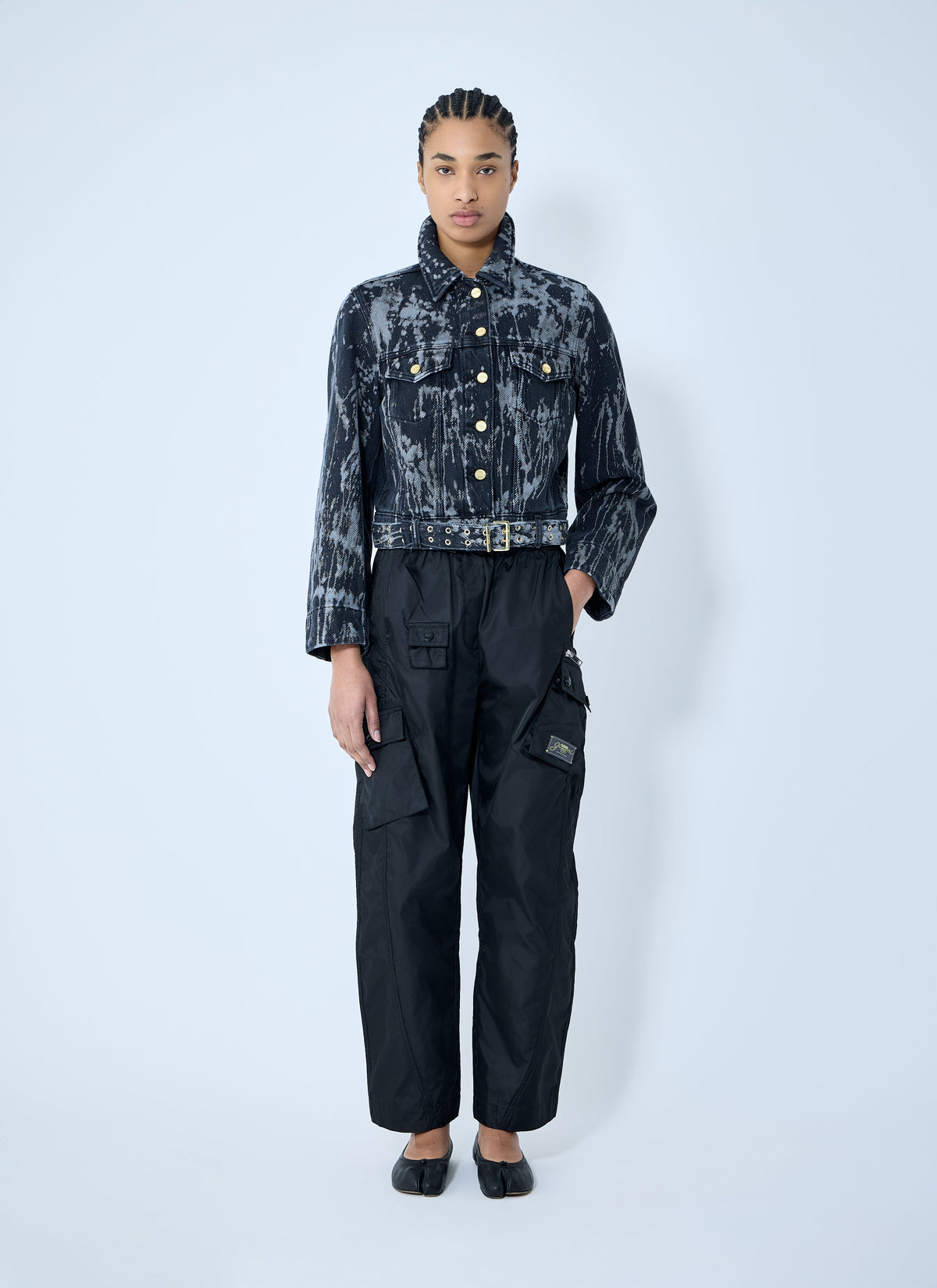 Person wearing a dark acid-wash denim jacket and black cargo pants on a white background