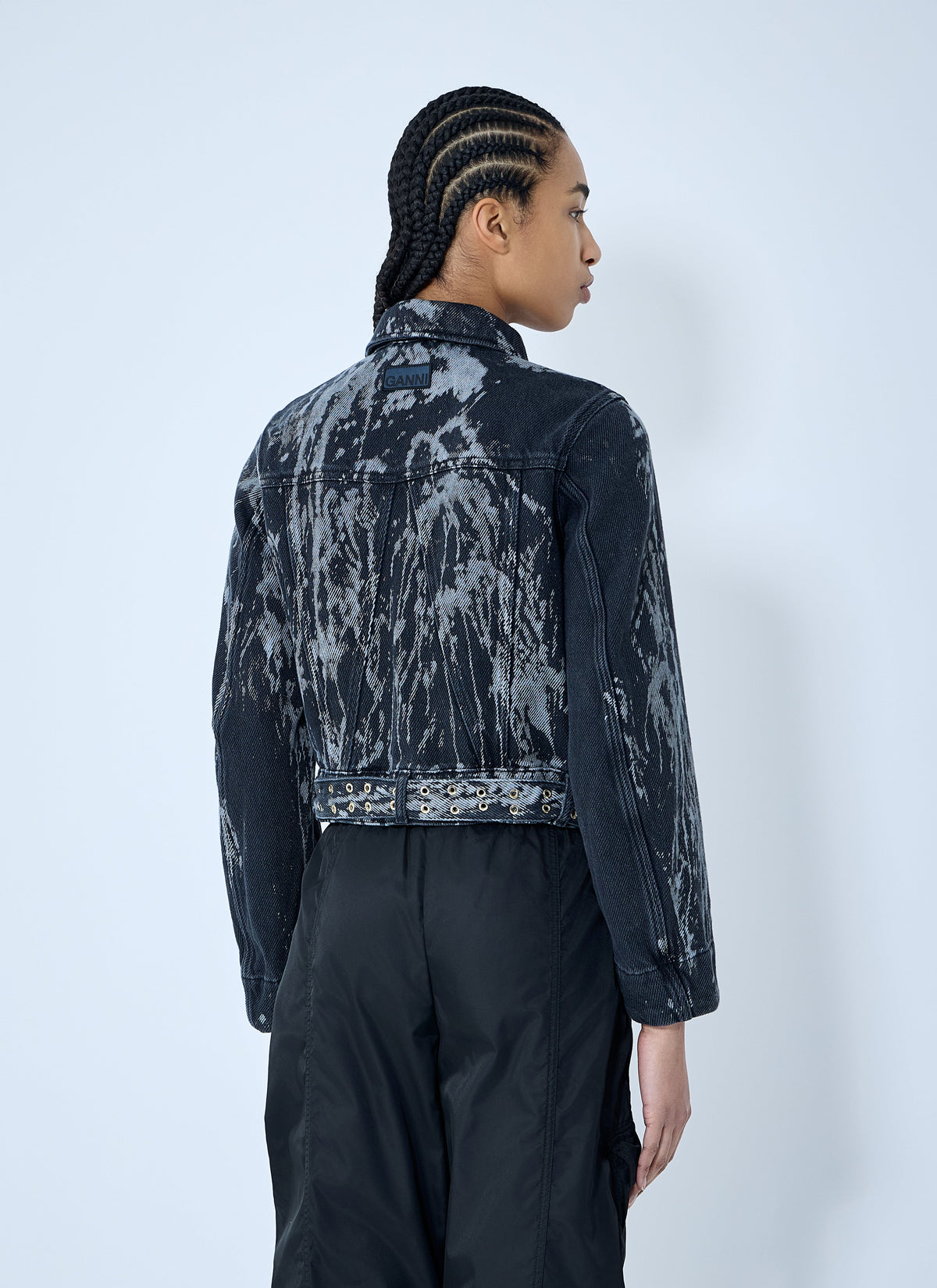 Person wearing a black and gray tie-dye denim jacket against a white background