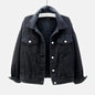 A black washed denim jacket hanging on a hanger against a light gray background. The jacket features a classic collar, a button-up front, and two buttoned chest pockets.