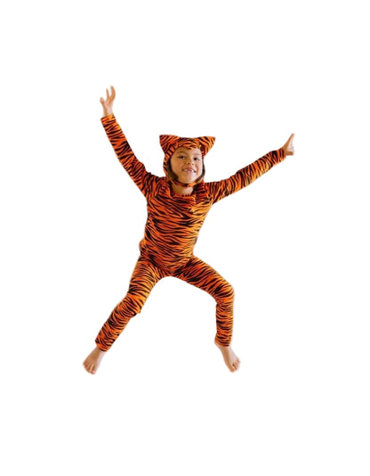 Child in a tiger-striped onesie jumping on a bed in a bedroom.