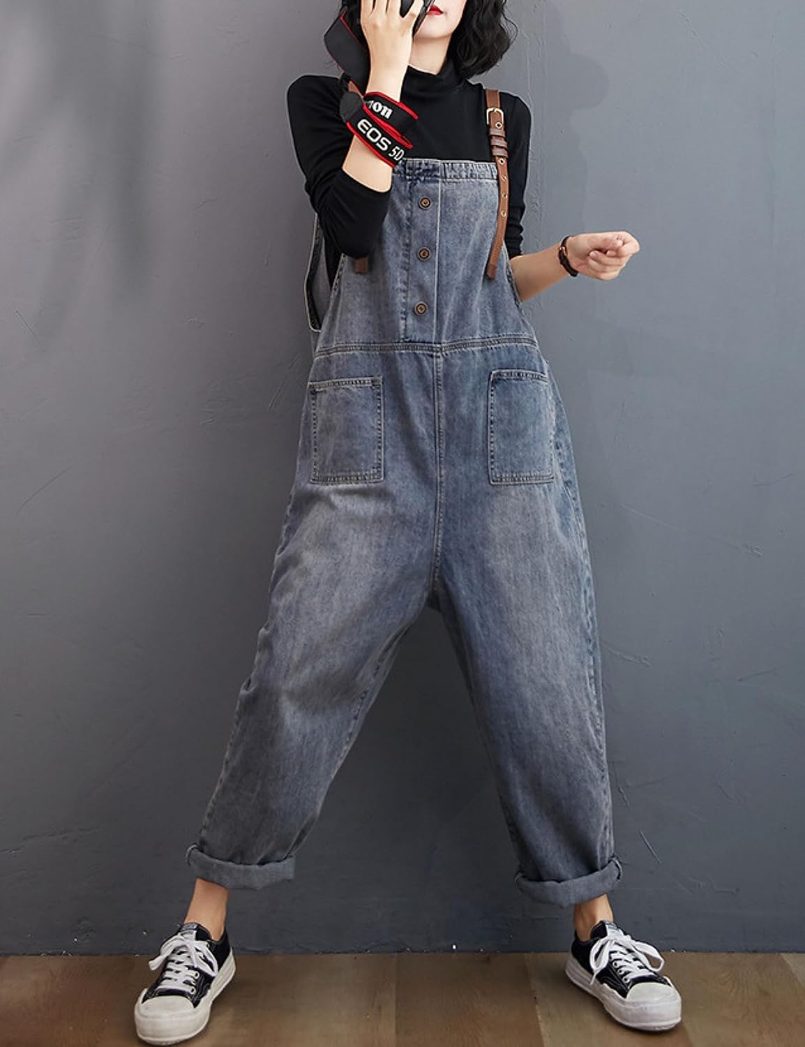 Person wearing denim overalls against a gray background