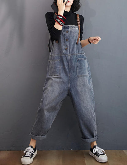 Person wearing denim overalls against a gray background